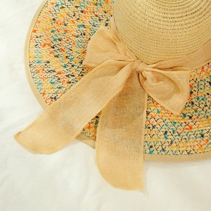 Detail of summer straw hat texture featuring colorful woven accents and a large bow ribbon