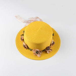 Flat top straw hat with pink floral accents and satin ribbon detail in macro view