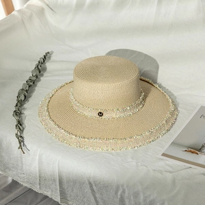Chapeau de paille beige chic avec bordure en tweed et logo M doré sur lin blanc