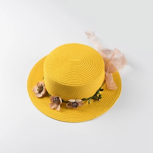 Detailed macro view of yellow straw boater hat with 3D floral accents and pink chiffon ribbon