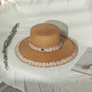 Détail d'un chapeau de paille marron avec bords effilochés en tweed et logo M doré
