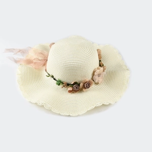Detail of a beige straw hat with scalloped edges and vintage rose wreath decor