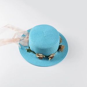 Detail of blue straw sun hat featuring a faux flower wreath and organza ribbon tie