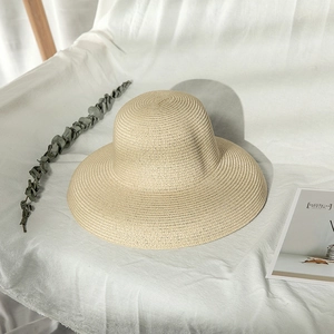 Detailed close-up of beige woven straw sun hat on a minimalist fabric surface with shadows