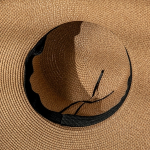 Détail de tissage serré du chapeau de paille avec bandeau noir et texture en spirale