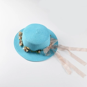 Detail of sky blue woven straw boater hat featuring champagne organza ribbon and floral decor