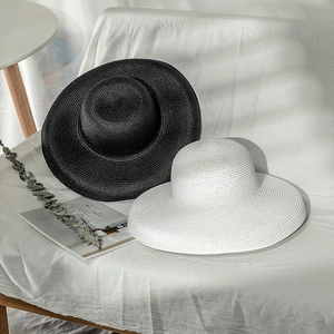 Close-up of black and white breathable wide brim straw sun hats on a white sofa