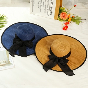 Detail of woven straw sun hats with elegant black chiffon bows and breathable texture