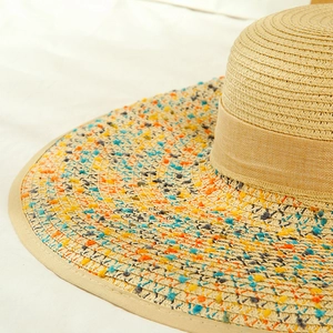 Detailed close-up of woven straw hat featuring colorful embroidery and ribbon trim