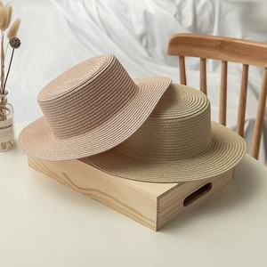 Close-up of beige and natural woven boater hats on a wooden tray with dried flowers