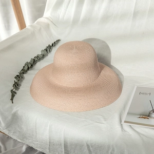 Elegant pink Audrey Hepburn style woven straw sun hat for women on white fabric