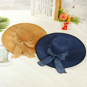 Close-up of woven straw sun hats in khaki and navy with large elegant decorative bows
