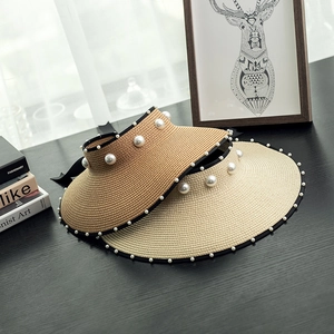 Close-up of straw sun visors with pearl accents and black satin bow details