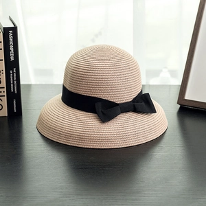 Detail of elegant khaki straw hat with a black ribbon bow on a dark wooden surface