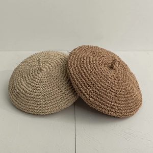 Gros plan de bérets en paille faits main en beige et kaki avec texture tissée
