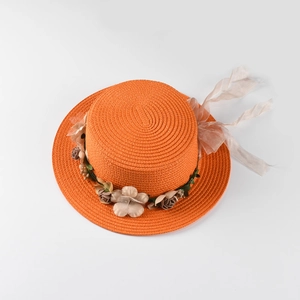 Detail of orange woven straw hat with floral wreath and organza ribbon for beach