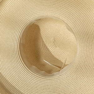 Detailed close-up of straw sun hat interior with adjustable strap and fine weaving texture