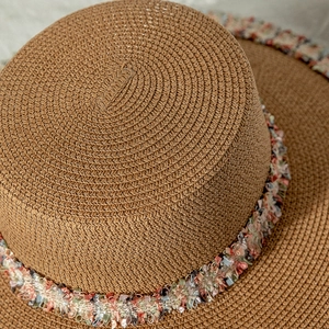 Détail de la texture d'un chapeau de paille tissé avec des finitions à franges colorées
