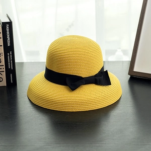 Detailed close-up of woven straw texture and black grosgrain ribbon bow on a sun hat