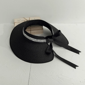 Detail of black straw visor with sequin trim and satin bow tie on white background