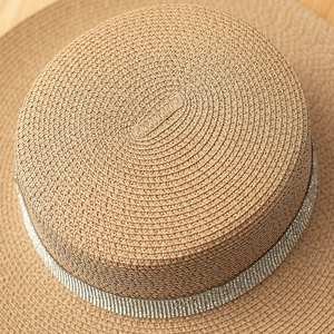 Detailed close-up of straw sun hat featuring a sparkling rhinestone band on light wood