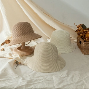 Detail of woven straw sun hats for girls in beige and brown with refined texture