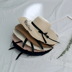 Gros plan sur des chapeaux de paille d'été avec broderie Sunshine et rubans noirs élégants