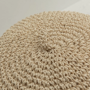 Vue détaillée du tissage en paille beige texturé et de la petite tige sur un béret d'été
