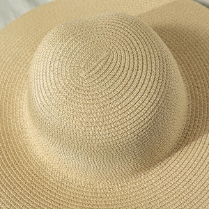 Close-up of beige foldable straw sun hat showing intricate spiral woven texture and details
