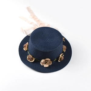 Detail of navy straw boater hat featuring floral wreath and long satin ribbon bow