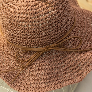 Detailed macro view of caramel straw sun hat with delicate suede bow and woven texture