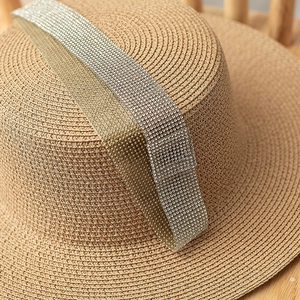 Detail of summer boater straw hat featuring sparkling rhinestones on tan woven texture