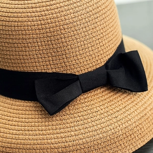Detail view showing textured straw weave and elegant black grosgrain ribbon bow on the sun hat