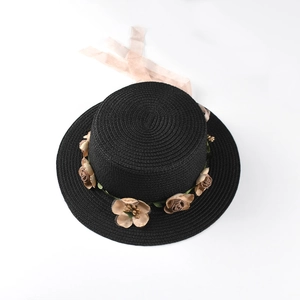 Detailed view of black boater straw hat with vintage floral decor and pink chiffon ribbon