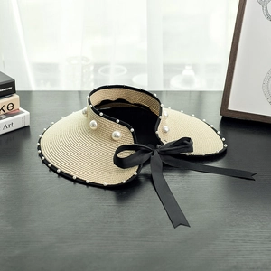 Women's beige straw sun visor with pearl embellishments and a black satin bow ribbon