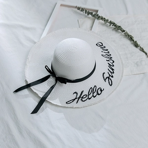 Détail d'un chapeau en paille blanc avec broderie Hello Sunshine et nœud en ruban