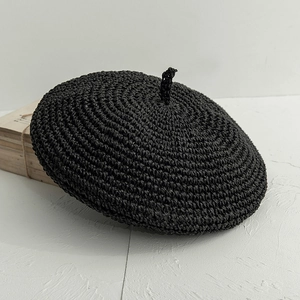 Gros plan détaillé d'un béret en paille crochetée noire montrant le tissage en spirale