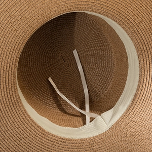 Close-up of brown straw hat interior showing the sweatband and adjustable drawstrings