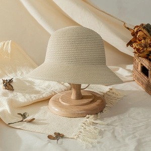 Handwoven straw sun hat for girls in beige displayed on a wooden stand for beach travel