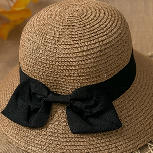 Detailed view of natural straw weave texture and a large black grosgrain ribbon bow
