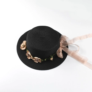 Detail of black straw hat featuring elegant brown satin ribbon and vintage rose floral decor