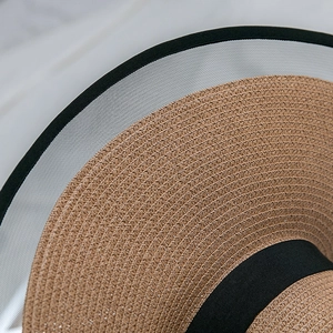 Close-up of woven straw texture with black mesh brim and elegant ribbon detail