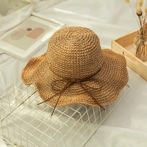 Close-up of hand-woven straw beach hat with bow tie detail and wavy brim texture