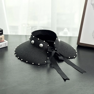 Close-up of black straw sun hat with pearl embellishments and a satin bow decoration