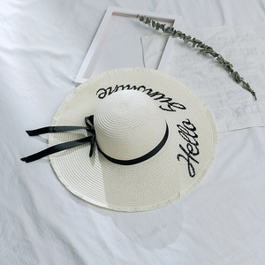 Détail d'un chapeau de paille à large bord avec broderie Hello Summer et ruban noir élégant