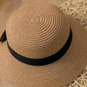 Close-up of the woven texture and black bow detail on a foldable straw sun hat
