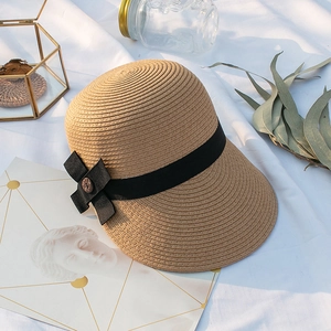 Détail d'un chapeau de soleil en paille beige avec ruban noir et nœud vintage élégant