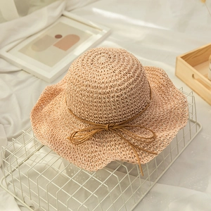 Close-up of hand-woven straw beach hat texture with elegant wavy brim and ribbon bow