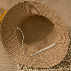 Macro shot of the straw bucket hat interior featuring sweatband and elastic windproof strap