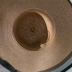 Detail view of woven straw texture and breathable black mesh edge on summer sun hat